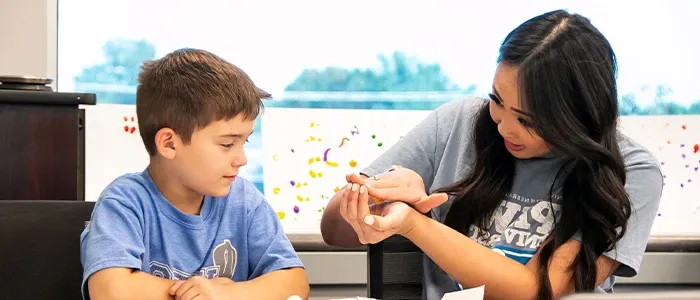 a speech pathology student works with a child in a classroom